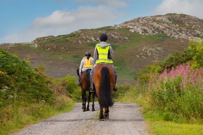 A pair of riders on horseback in the lush countryside in Wales