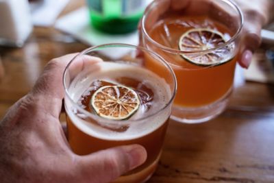 Couple sharing an intimate moment as they clink together highball glasses with refreshing icy cocktails