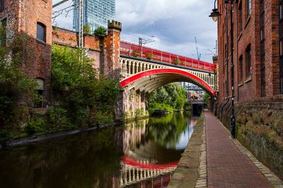 Manchester canal towpath with red-and-white cast-iron Cornbrook viaduct in background