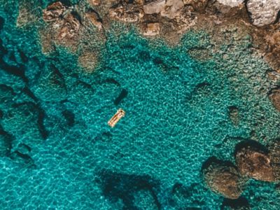 A woman relaxing on a floating lounger in turquoise waters in the Ionian Sea, Greece
