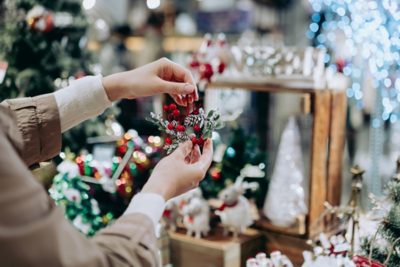 Close up of young woman doing Christmas shopping, holding a Christmas wreath decoration in retail store in festive Christmas season.