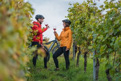 Couple de cyclistes dégustant un verre de vin bordelais dans les vignes