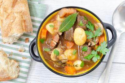 Cassolette de ragoût de bœuf et morceaux de pain, sur la table d’un bistrot de quartier à Paris