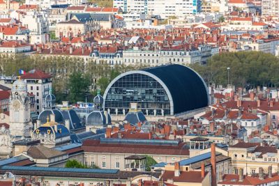 Edificio moderno curvo de la Ópera de Lyon sobresaliendo entre tejados clásicos franceses