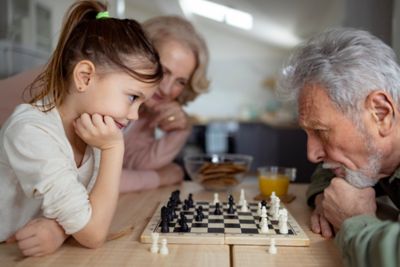 A child and grandparent facing off in a game of chess