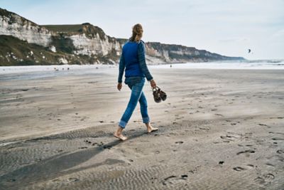 A barefooted traveller indulging in alone time with a walk on a sandy beach