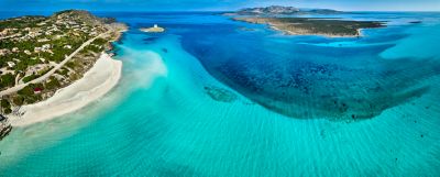 A white-sand beach in Sardinia with an expanse of turquoise shallows and cobalt blue depths