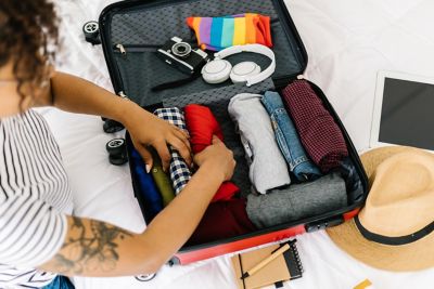 Clothes and other travel essentials being neatly packed into a small suitcase