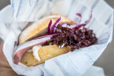 Fischbrötchen mit Hering, Salat und Zwiebeln in hellem Papier