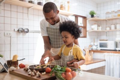 A parent and child cooking together with fresh ingredients