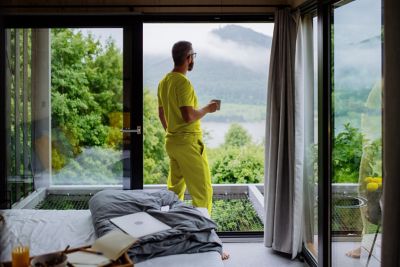 Un homme adepte du nomadisme digital boit un café dans sa chambre d’hôtel