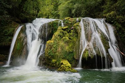 A waterfall in an ethereal green forest in the Jura Mountains, France