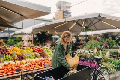 Femme chargeant ses courses sur un vélo cargo au marché
