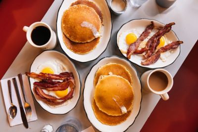 American-style pancakes alongside plates of bacon and eggs in a restaurant