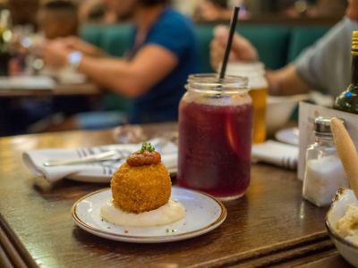 Primer plano de una bomba, tapa típica de Barcelona, con un tinto de verano, en un restaurante