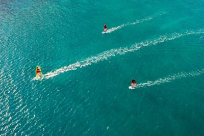 A trio of windsurfers in clear, turquoise waters in Greece