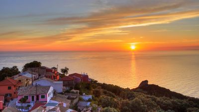 Agios Gordios bay in Corfu, Greece, with a quiet village overlooking the Ionian Sea at sunset