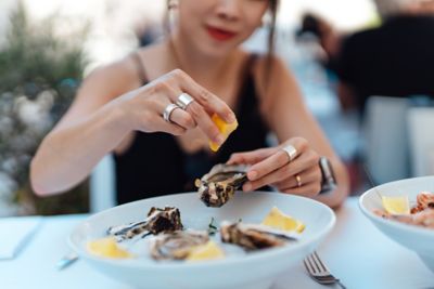 A diner squeezing lemon on a fresh oyster, a popular type of French seafood