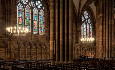 Interior gótico con coloridas vidrieras iluminadas y grandes lámparas de hierro