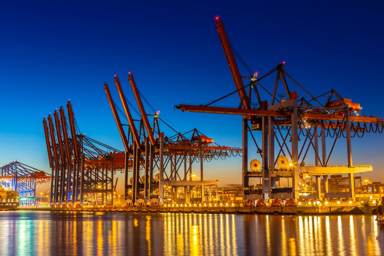 Industriewerft mit großen Hafenkränen in Hamburg bei Sonnenuntergang