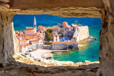 Budva Old Town with a church spire and orange rooftops surrounded by the Adriatic Sea