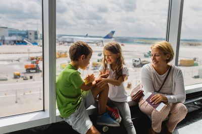 Une mère et ses deux enfants qui patientent sans stress à l’aéroport lors d’un départ en voyage