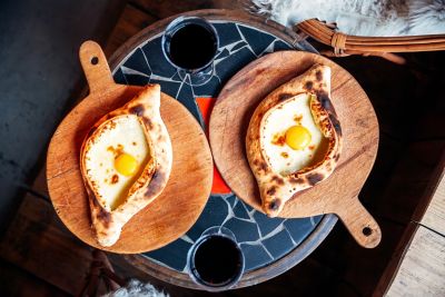 Golden-brown adjaruli khachapuri, a Georgian boat-shaped bread with a raw egg yolk