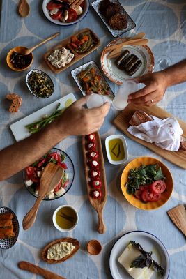 Zwei Personen stoßen mit kleinen Gläsern Raki oder Ouzo über einem Tisch voller Meze an