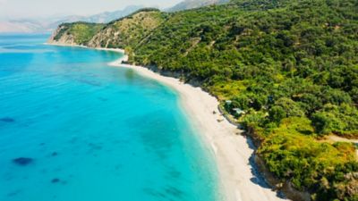White sands and forested hills meeting the turquoise Adriatic Sea on Albania's coast