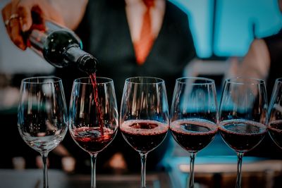 Red wine being poured into shiny long-stemmed glasses at a fine dining restaurant