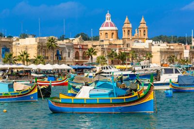 Colourful fishing boats in palm-lined Marsaxlokk Harbour, Malta