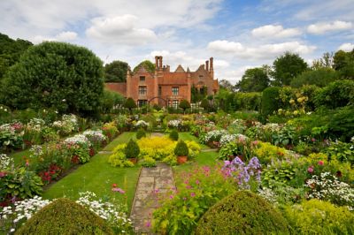 Chenies Manor near Watford, with vibrant flowerbeds fronting a red-brick mansion