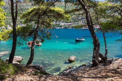 Croatian bay with clear blue waters, sailboats and swimmers