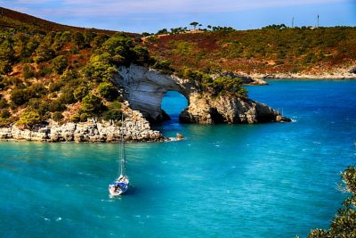 A yacht in calm blue waters on the quiet, rocky Sant’Antioco coast in Sardinia