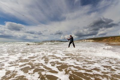 A kitesurfer in the foamy shallows of Compton Bay, Isle of Wight