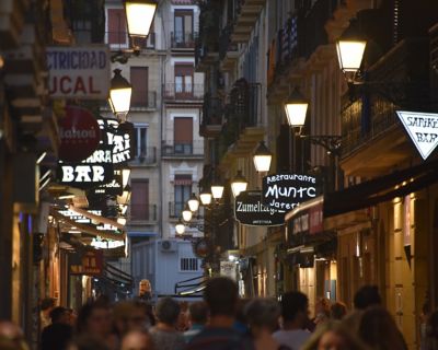 Eine schmale, belebte Gasse in der Altstadt von San Sebastián mit vielen Bars in der Dämmerung