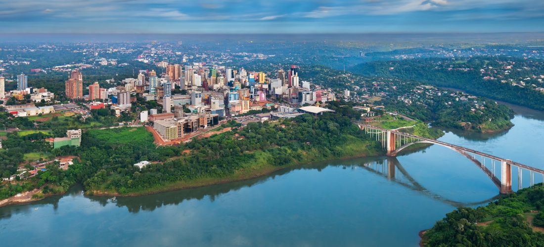 Aerial view of city and river landscape Ciudad del Este Skyline & Friendship Bridge at Sunset 