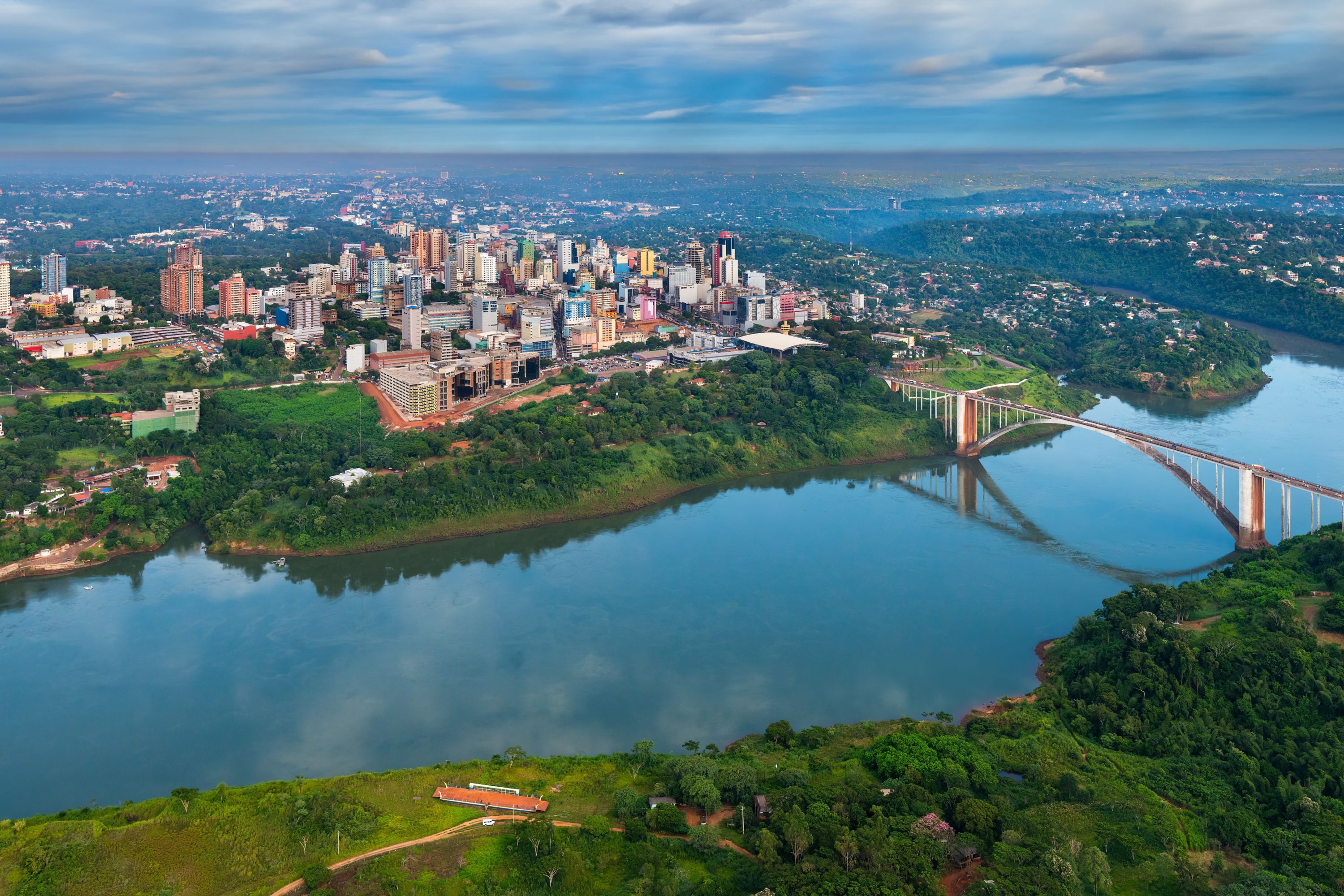 Aerial view of city and river landscape Ciudad del Este Skyline & Friendship Bridge at Sunset 