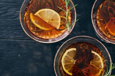 A sophisticated cocktail in a crystal glass, garnished with orange and rosemary