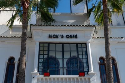The whitewashed exterior of Rick’s Café, flanked by palm trees, in Casablanca
