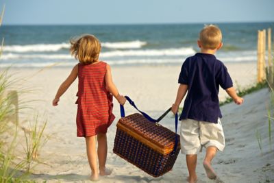 Enfants qui portent un panier à pique-nique sur une plage en Bretagne