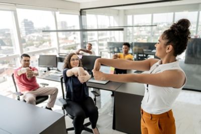 Colleagues engaged in active sitting by stretching together in the office 