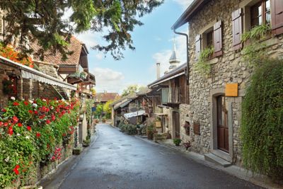 Stone houses with colourful flowers on a quiet lane in Yvoire, Haute-Savoie