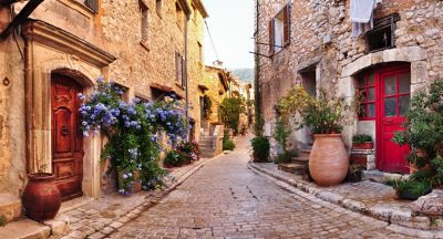 Stone houses with colourful flowers lining a quaint cobbled street on the French Riviera