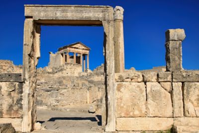 Ruinas romanas de Dougga con un templo visible a través de un arco de piedra