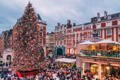 Mercado navideño bullicioso en Covent Garden, con un enorme árbol decorado