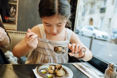 A child enjoying escargots in a French restaurant in Paris