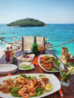 A table set with platters of Albanian seafood, by the Mediterranean Sea