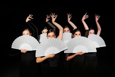 A group of flamenco dancers in Spain posing dramatically with white fans and raised arms