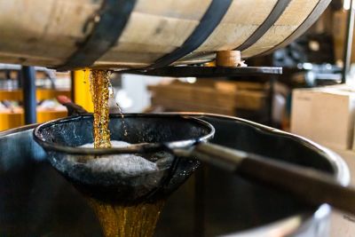 Golden whiskey being poured from a barrel at a distillery